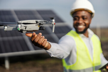 Close up of black maintenance engineer catching drone at solar power plant.