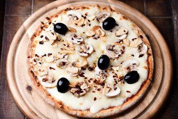 Pizza with champignons, black olives and mozzarella cheese. Wooden background. Soft focus.