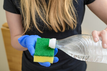 a woman is cleaning, she has gloves on her hands, she uses spirit vinegar to clean