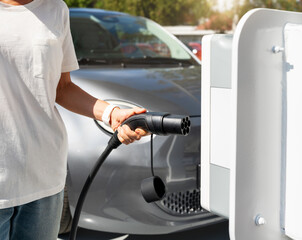 Woman charging her electric car at an EV charging station in city