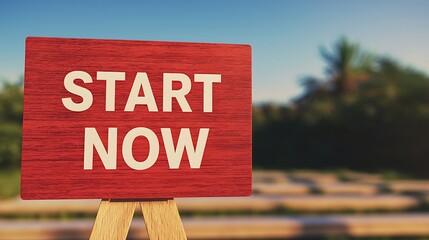 A red sign reading "START NOW" in a serene outdoor setting, encouraging immediate action and motivation.