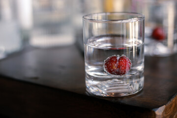 Selective focus Violet Plum in a clear soda glass with bubbles in the clear water and space for text.