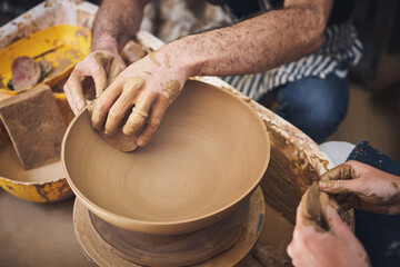 Hands, clay and bowl on pottery wheel for ceramic shaping, manufacturing process or sculpture sponge. Above, people and design teamwork in workshop for small business, handcraft or production closeup