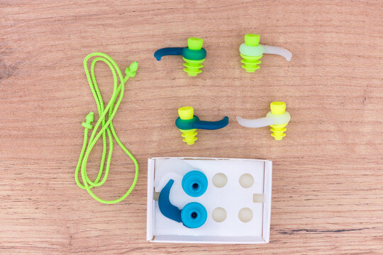 Close up of ear protection plugs from water and noise, suitable for swimming, snorkeling and diving. Rubber earplugs of different sizes and colors isolated on wooden background