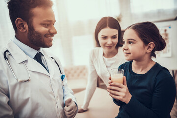 Obraz premium Indian doctor seeing patients in office. Doctor is giving pop pill and water to daughter.
