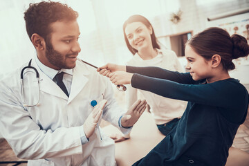 Indian doctor seeing patients in office. Daughter is pulling stethoscope.