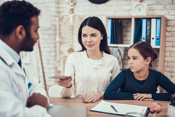 Obraz premium Indian doctor seeing patients in office. Mother is giving money to doctor.