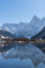 Fototapeta premium Dombay, Karachay-Cherkessia. Teberda National Park. Lake Tumanly-Gel or Tumanly-Kol (Misty Lake) is in valley of Gonachkhir River. Snowy peaks of Mount Chotcha are reflected in lake as in mirror.