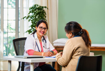Indian Young female doctor discussing medical case report with senior patient in a lavish clinic