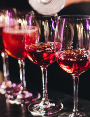 Bartender working, barman mixing and pouring drinks and beverages in a club, beautiful row line of different red coloured liquor alcohol cocktails on a party in a bar, catering banquet on event