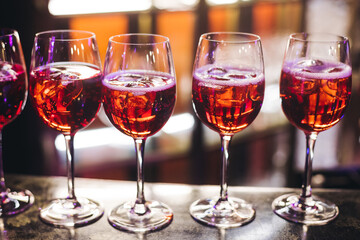 Bartender working, barman mixing and pouring drinks and beverages in a club, beautiful row line of different red coloured liquor alcohol cocktails on a party in a bar, catering banquet on event