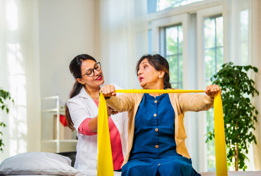 Doctor or physiotherapist assisting senior patient with theraband exercise for shoulder pain relief