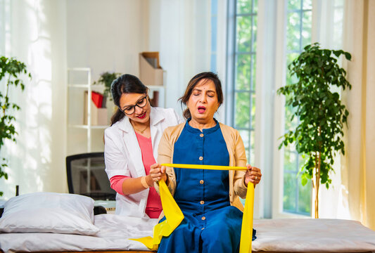 Doctor or physiotherapist assisting senior patient with theraband exercise for shoulder pain relief
