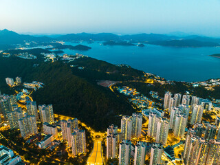 Aerial panorama of Hong Kong city at dusk. Buildings illuminate the landscape as twilight descends...