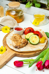 Grilled chicken and vegetables on a wooden board, restaurant.