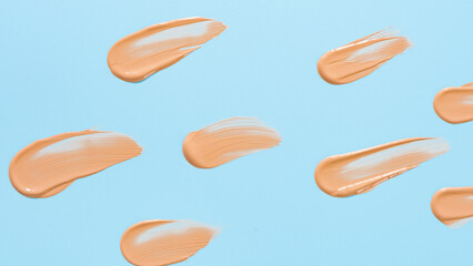 Makeup foundation texture swatch. BB cream, concealer, paint smear on blue background. 