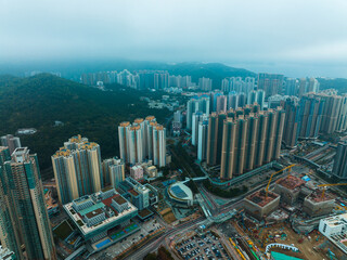 Aerial panorama of Hong Kong, China, showcasing dense urban cityscape with high-rise buildings, green hills, and cloudy sky. © YiuCheung