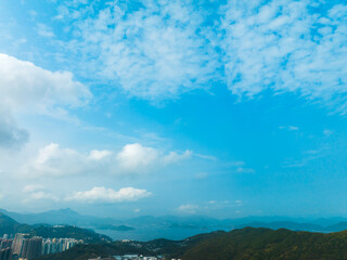 Aerial panorama of Hong Kong city showcasing mountains and sea under a bright sky. A scenic urban landscape from a high vantage point.
