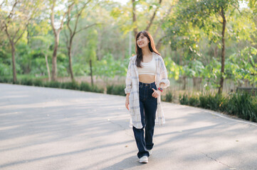 Asian woman enjoying summer walk, breathing fresh air in serene park, wearing casual attire with...