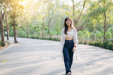 Asian woman enjoying summer day, walking outdoors and breathing fresh air in serene park with...