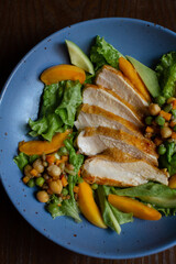 juicy fried chicken with vegetables and sweet peaches on a blue plate