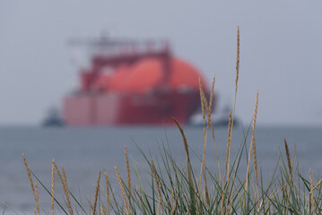 LNG TANKER - Grass on dunes seashore and red ship