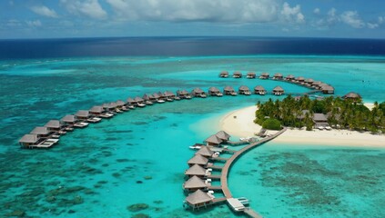 Obraz premium This stunning tropical location features luxurious overwater bungalows, clear turquoise waters, and lush palm trees under a bright blue sky, inviting relaxation and adventure