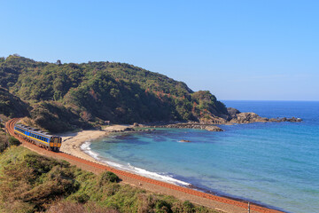 紺碧の折居海岸に沿って走る山陰本線を望む