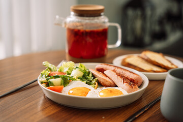Fried sausages with eggs raspberry tea for breakfast.