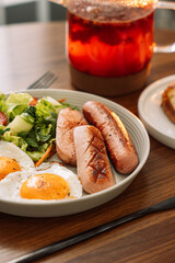 Fried sausages with eggs raspberry tea for breakfast.