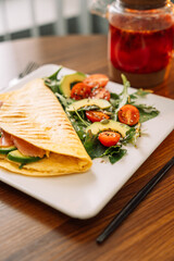 Tortilla with salmon with salad in a square white plate.