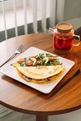 Tortilla with champignons with salad in a square white plate.