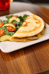 Tortilla with champignons with salad in a square white plate.