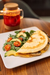 Tortilla with champignons with salad in a square white plate.