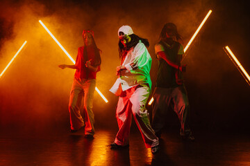 Fototapeta premium Group of hip hop dancer dancing together in a moody studio with tube neon lights.