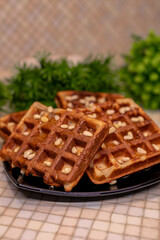 On the table sits a delicious plate of waffles adorned with nuts