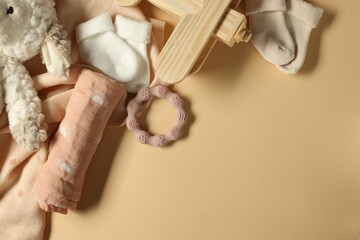 Baby blankets, toys, socks and teether on beige background, flat lay. Space for text