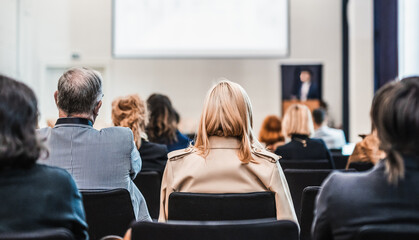 Speaker giving a talk in conference hall at business event. Rear view of unrecognizable people in...