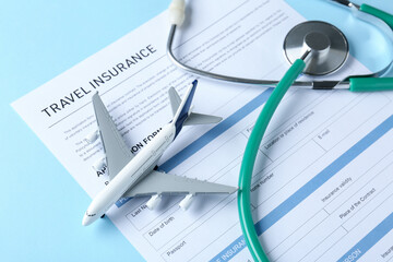 Medical tourism. Travel insurance application form, stethoscope and plane model on light blue background, closeup