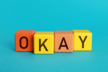 Obraz premium Colorful cubes with word Okay on light blue background