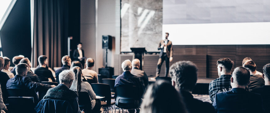 Speaker giving a talk in conference hall at business event. Rear view of unrecognizable people in audience at the conference hall. Business and entrepreneurship concept