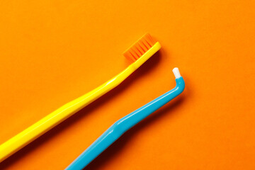 morning and evening routine dental care from caries tools like toothbrush and tuft toothbrush on orange background