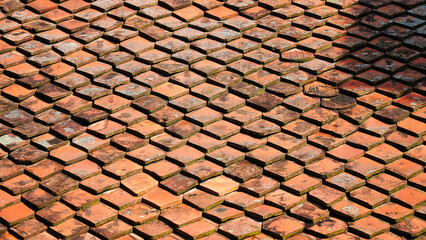 old roof with red traditional tiles in romania.Sunlight casts shadows on an intricate pattern of hexagonal terraco.Hexagonal terracotta tiles create a rustic and textured surface in a sunlit courtyard