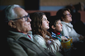 Multigenerational family watching a movie in cinema with popcorn