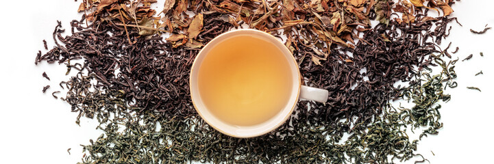 Loose tea leaves and a cup of tea panorama. Black, green, and white teas in heaps, overhead flat...