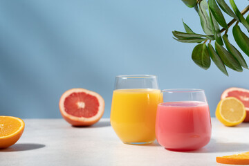 Orange and grapefruit refreshing drink on blue background. Smoothie, juice or citrus cocktail side view
