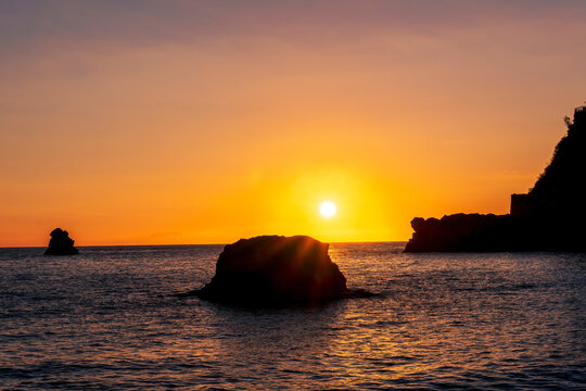 scenic sea shore view of island in ocean with waves and amazing cloudy sunset or sunrise on backgeound