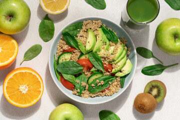Quinoa spinach avocado salad on light background surrounded by fruits, smoothie and spinach leaves. Healthy food concept