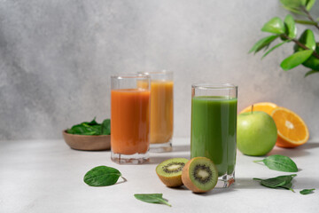 Detox healthy drinks in glasses on light background. Green, yellow and orange smoothie close-up view