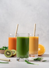 Detox healthy drinks in glasses on light background. Green, yellow and orange smoothie close-up view